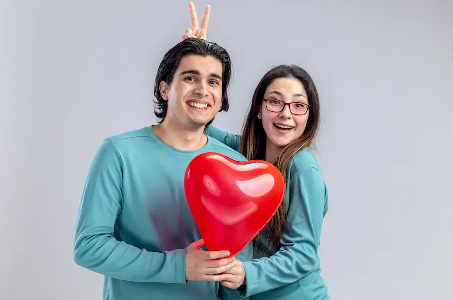 Pareja joven en el día de San Valentín niña sonriente haciendo gesto de oreja