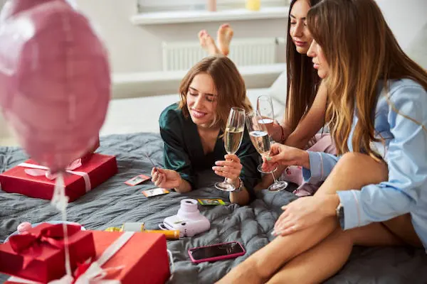 Futura novia sonriendo mientras abraza con afecto a sus mejores amigas durante una reunión previa a la boda.
